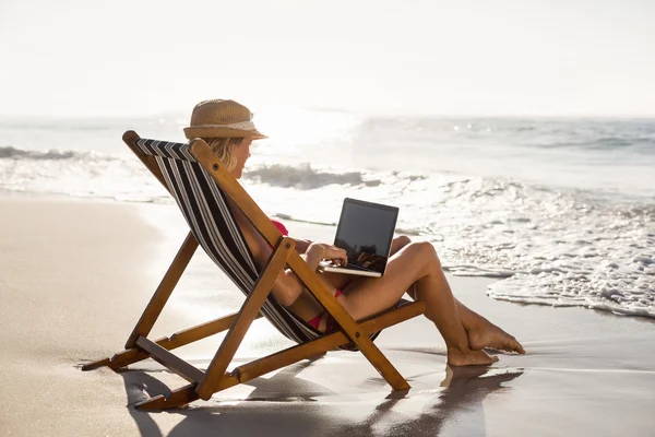Vrouw zittend op een stoel en het gebruik van een laptop — Stockfoto