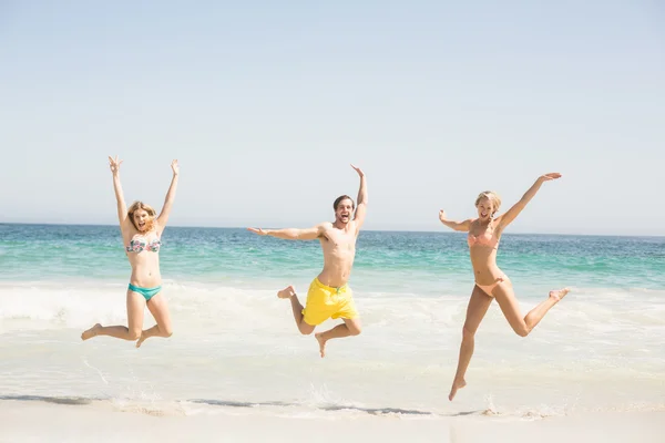 Joyeux jeunes amis sautant sur la plage — Photo