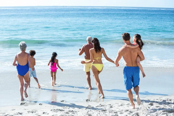 Família bonito multi geração correndo no mar — Fotografia de Stock