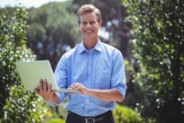 Homem de negócios bonito usando laptop — Fotografia de Stock