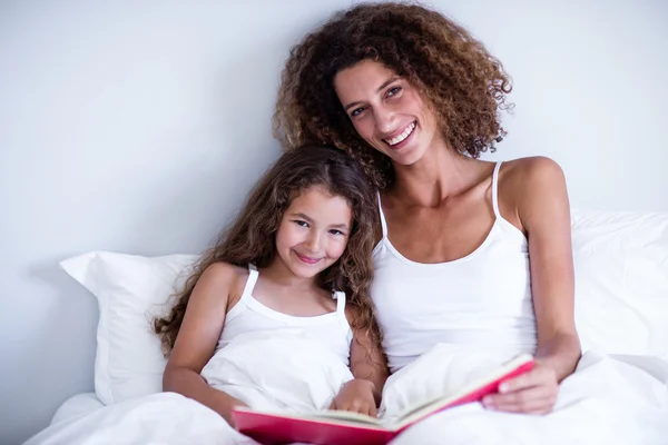 母と娘のベッドの上の本を読んで — ストック写真