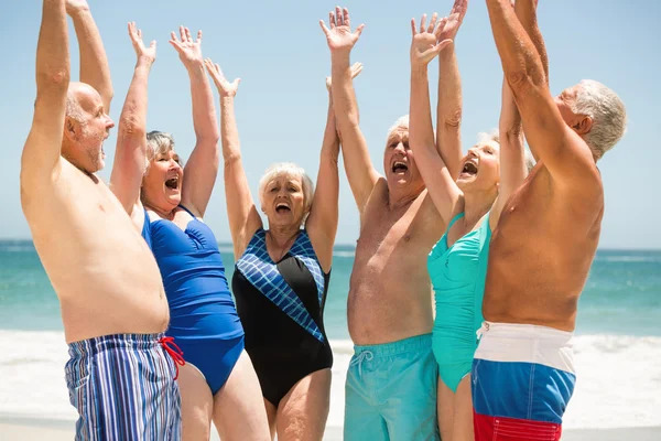 Seniorer med händer upp på stranden — Stockfoto