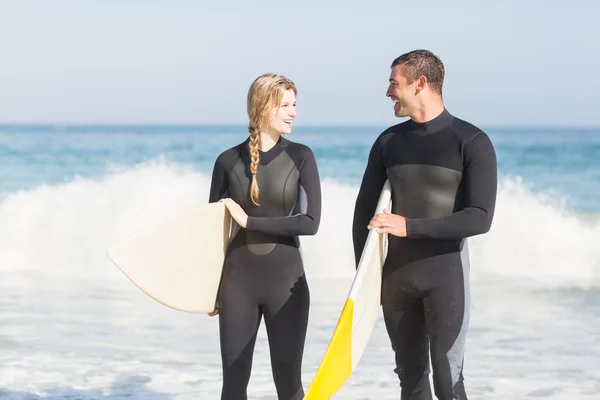 Paar mit Surfbrett am Strand spazieren — Stockfoto