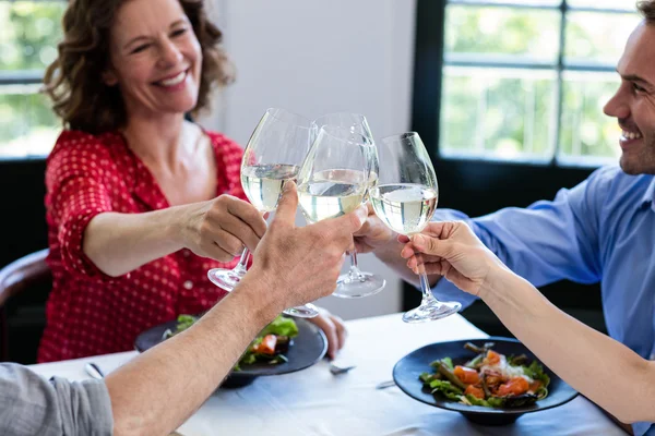 Szczęśliwy przyjaciele opiekania kieliszek do wina przy obiedzie — Zdjęcie stockowe