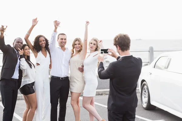 Pessoas bem vestidas tirando fotos ao lado de uma limusine — Fotografia de Stock