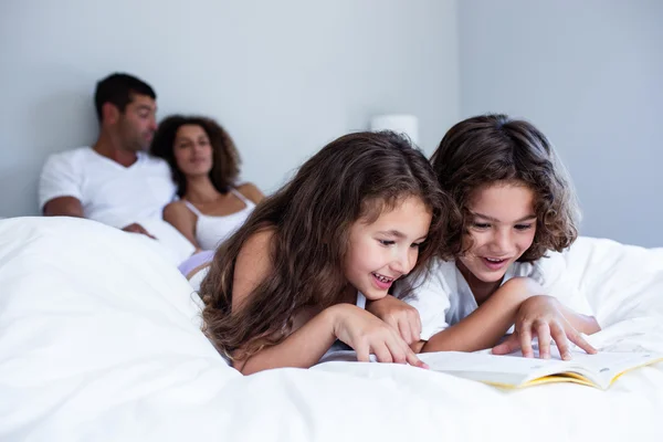 Hermano y hermana leyendo libro en la cama —  Fotos de Stock