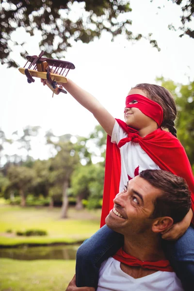 Dívka v kostýmu superhrdiny na otce ramena — Stock fotografie