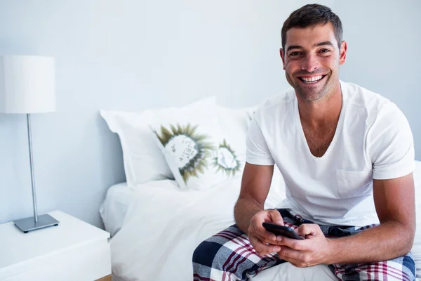 Hombre sentado en la cama y escribiendo un mensaje de texto — Foto de Stock