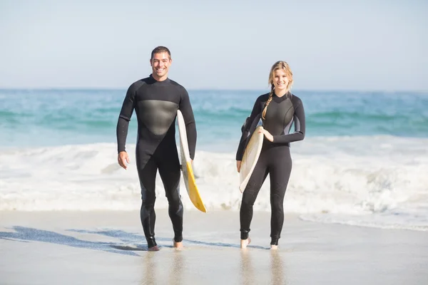 Koppel met surfboard wandelen op het strand — Stockfoto