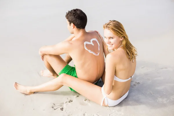 Woman making a heart symbol on mans back — Stock Photo, Image