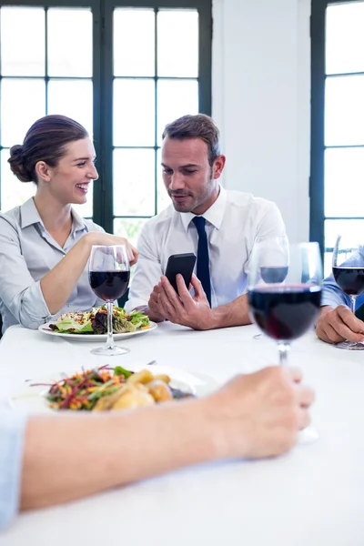 Obchodní přátelé, při pohledu na mobilní telefon — Stock fotografie