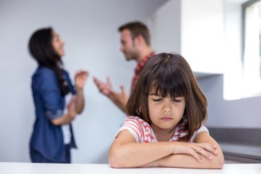 Sad girl hearing her parents arguing clipart