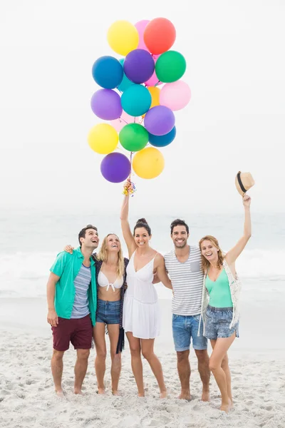 Groep vrienden permanent op het strand met ballonnen — Stockfoto