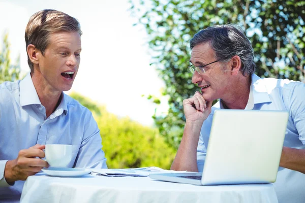 Два бизнесмена встречаются в ресторане с помощью ноутбука — стоковое фото