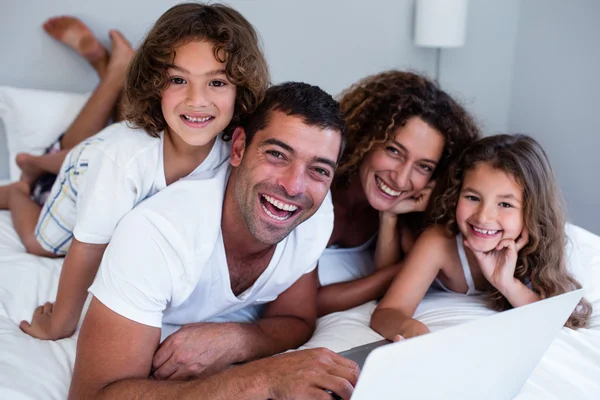 Ritratto di famiglia usando il computer portatile insieme sul letto — Foto Stock