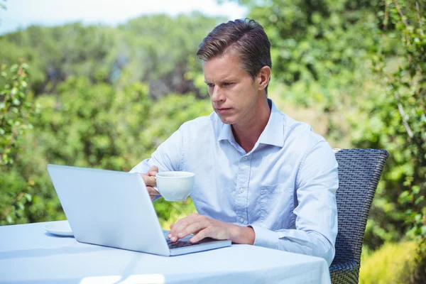 Hombre de negocios serio usando el ordenador portátil con café —  Fotos de Stock