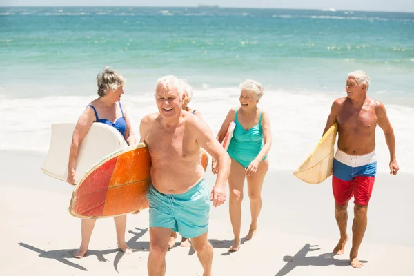 Seniorzy prowadzenie deski surfingowe na plaży — Zdjęcie stockowe