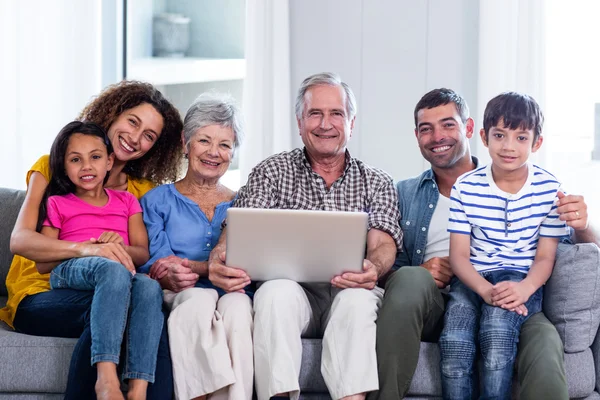 Porträtt av lycklig familj med laptop på soffa — Stockfoto