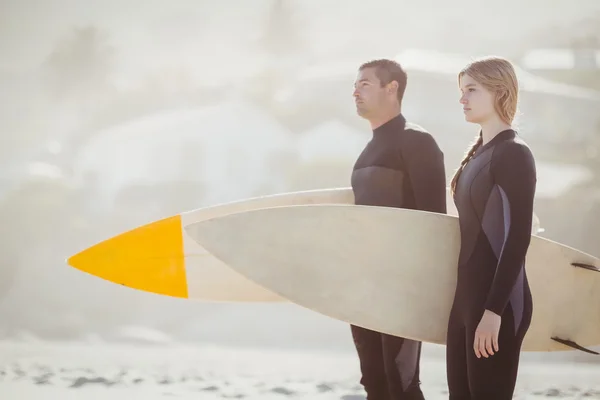 Casal com prancha de surf em pé na praia — Fotografia de Stock