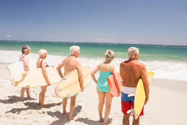 Amigos mayores sosteniendo tabla de surf — Foto de Stock