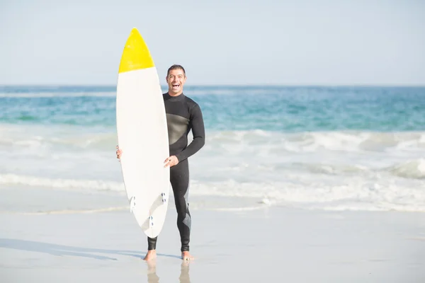 Ευτυχισμένος άνθρωπος που κατέχει μια σανίδα του σερφ στην παραλία — Φωτογραφία Αρχείου