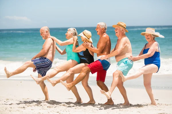 Пожилые люди танцуют подряд на пляже — стоковое фото