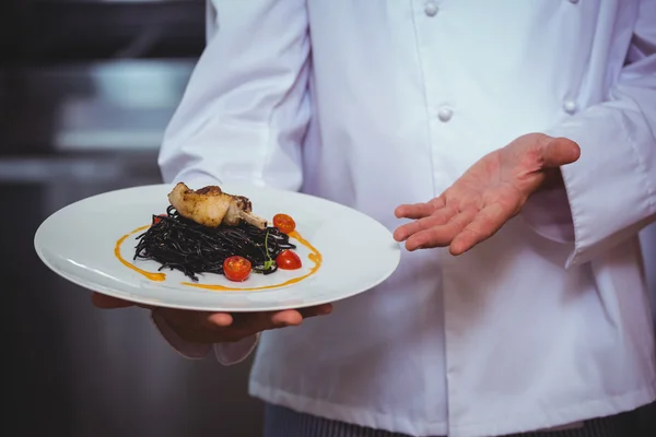 Proud chef holding a plate of squid ink spaghetti — Stock Photo, Image