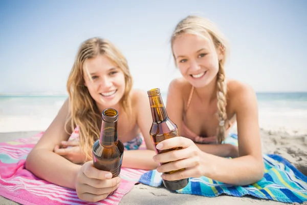 Glada kvinnor ligga på stranden med ölflaska — Stockfoto