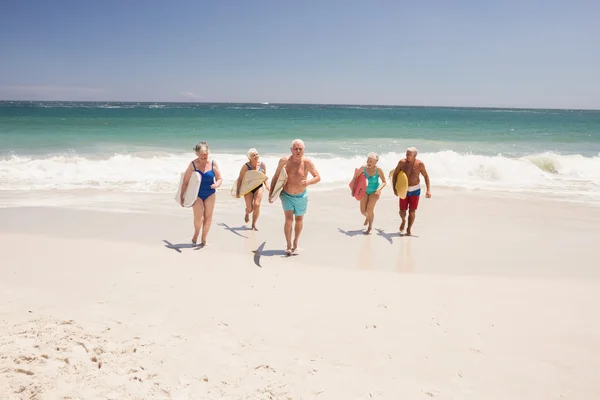 Amigos mayores sosteniendo tabla de surf — Foto de Stock