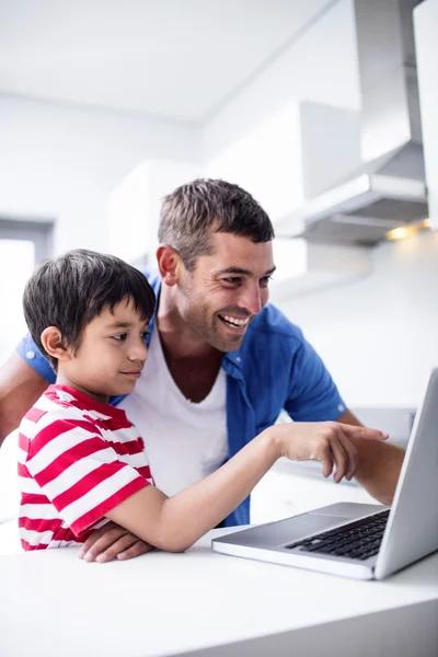 Pai e filho usando laptop na cozinha — Fotografia de Stock