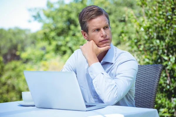 Pensativo hombre de negocios utilizando el ordenador portátil con café —  Fotos de Stock