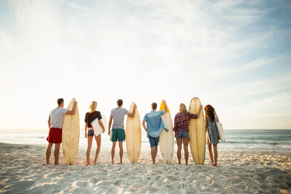 Amigos sosteniendo tabla de surf en la playa —  Fotos de Stock