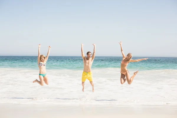 Joyeux jeunes amis sautant sur la plage — Photo