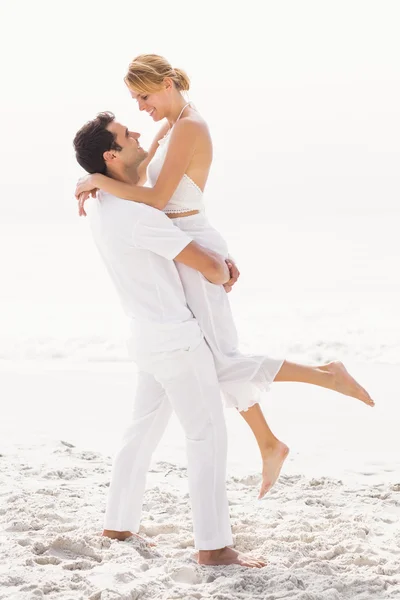 Uomo sollevamento donna sulla spiaggia — Foto Stock