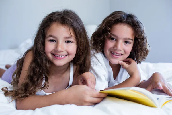 Bror och syster läser bok på sängen — Stockfoto