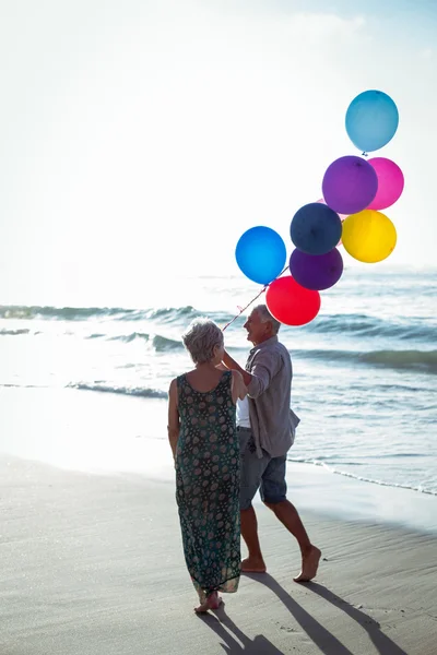 Pareja mayor sosteniendo globos — Foto de Stock