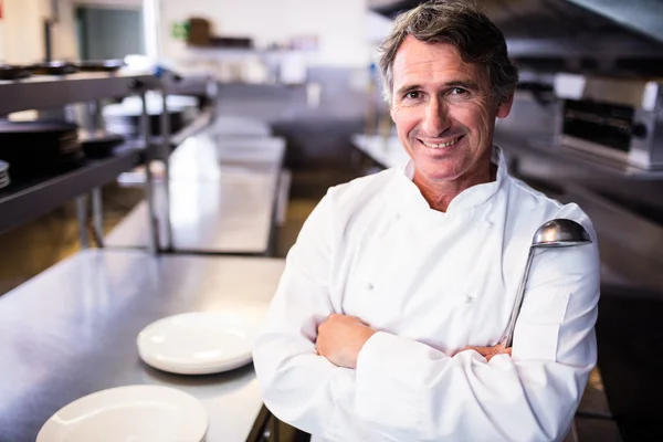 Chef sorridente che tiene mestolo in cucina — Foto Stock