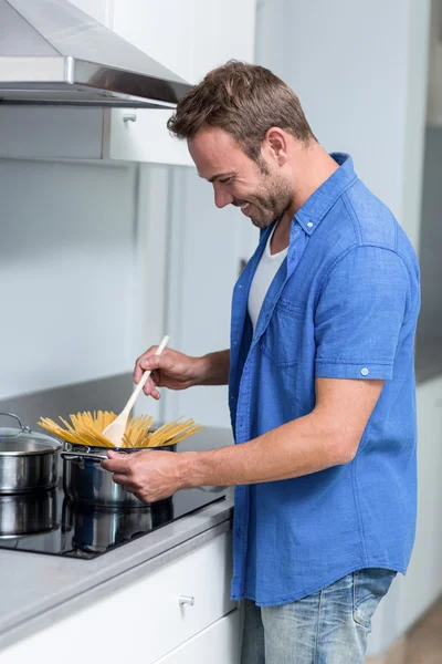 Junger Mann kocht Spaghetti — Stockfoto