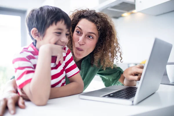 Madre e figlio utilizzando il computer portatile in cucina — Foto Stock