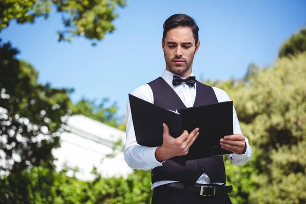 Handsome waiter looking at the menu — Stock Photo, Image