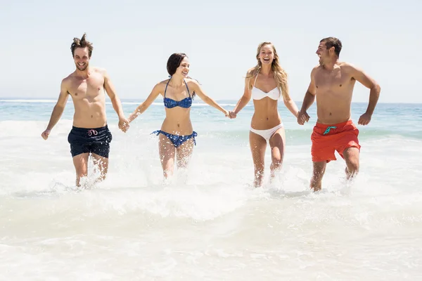 Friends holding hands and running on the beach — Stock Photo, Image