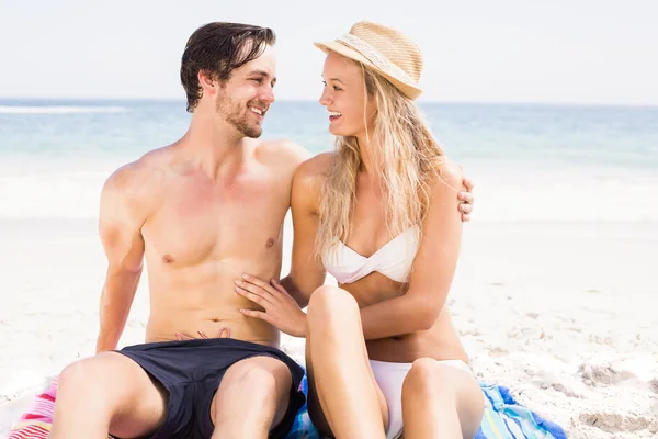 Jovem casal sentado e falando na praia — Fotografia de Stock