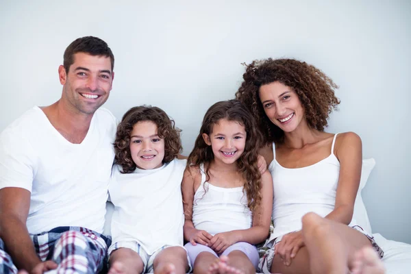 Portrait of a family sitting together on bed — Stock Photo, Image