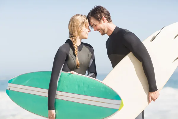 Couple standing head to head with surfboard — Stock Photo, Image