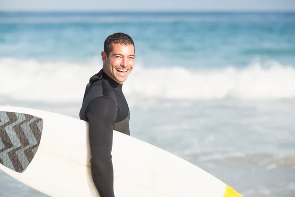 Homem feliz segurando uma prancha na praia — Fotografia de Stock