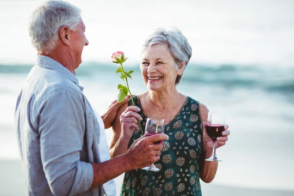 Ανώτερος ζευγάρι κρατώντας τριαντάφυλλο και κόκκινο ποτήρια κρασιού — Φωτογραφία Αρχείου