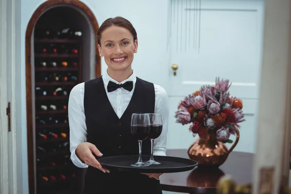 微笑女服务员端着一杯红酒与托盘 — 图库照片