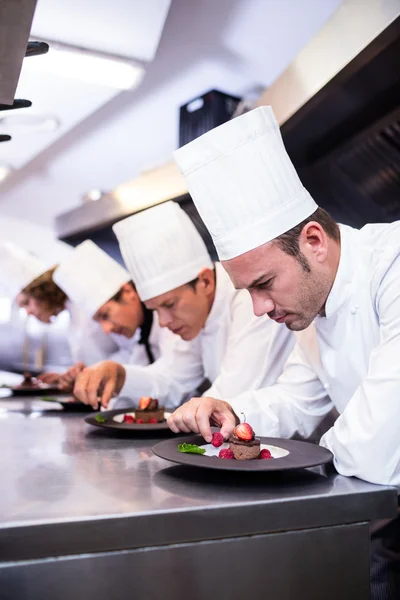 Chefs finishing dessert plates in kitchen — Stock Photo, Image