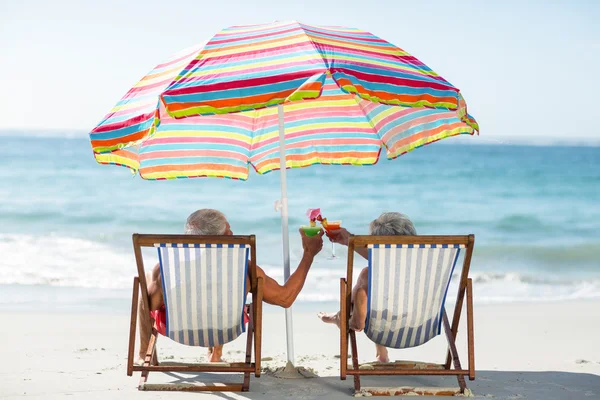 Cute mature couple lying on deckchairs — Stock Photo, Image