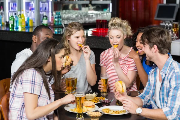 Amigos felizes tomando uma bebida e hambúrguer — Fotografia de Stock